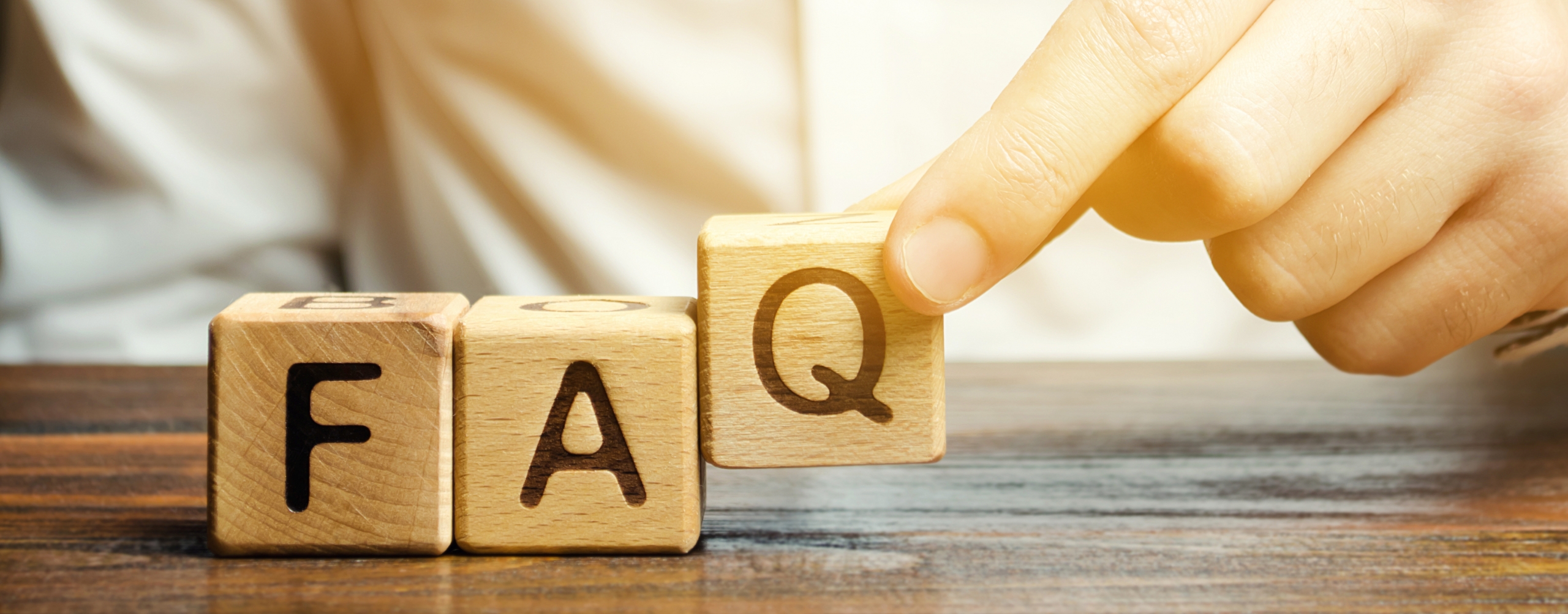 Hand stellt Holzwürfel mit den Buchstaben F, A und Q auf