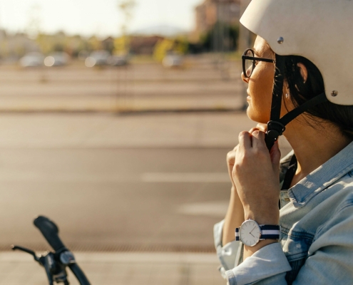 Junge Frau setzt sich einen Fahrradhelm auf