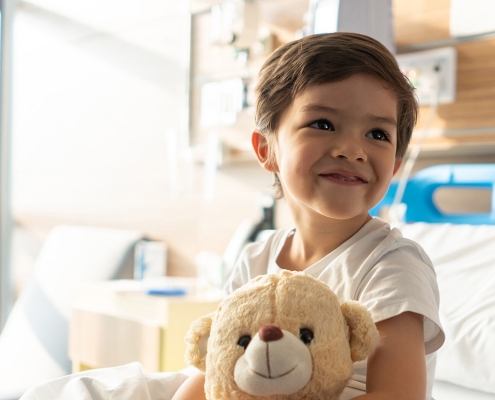 Kind mit Teddy-Bär auf Bett